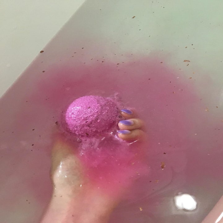 hand holds bath bomb under water 