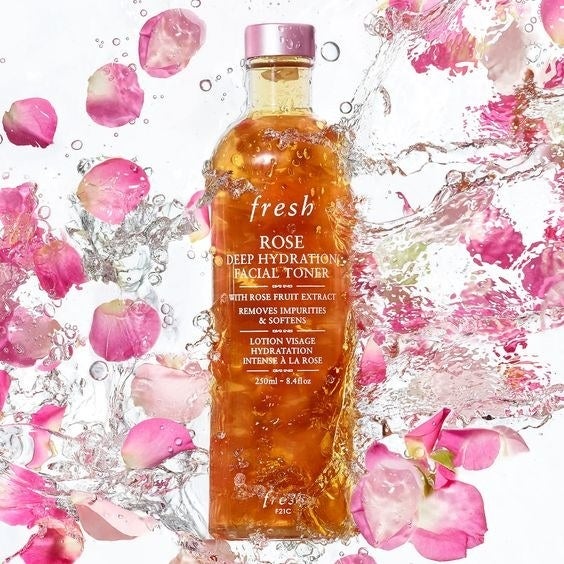 A bottle of toner submerged in water with rose petals