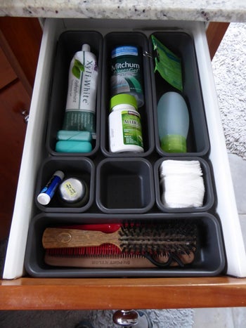 The same reviewer's cluttered toiletries looking neatly organized in storage bins