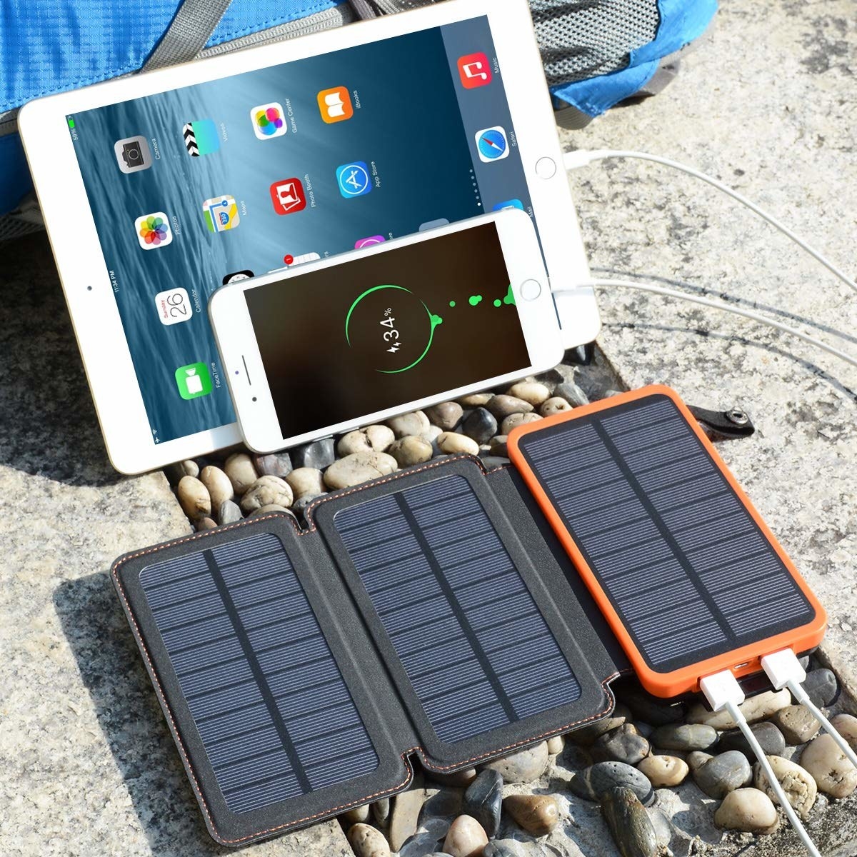 The solar bank resting on a rock with gadgets plugged into it