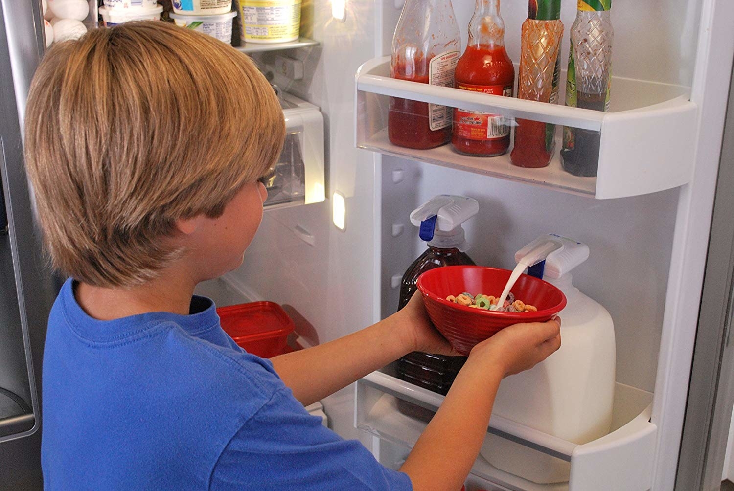 Child pushing bowl of milk against tap, dispensing milk from jug without picking it up