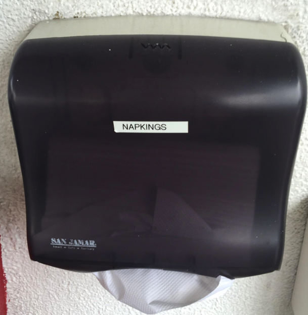 Paper towel dispenser labeled &quot;napkings&quot;