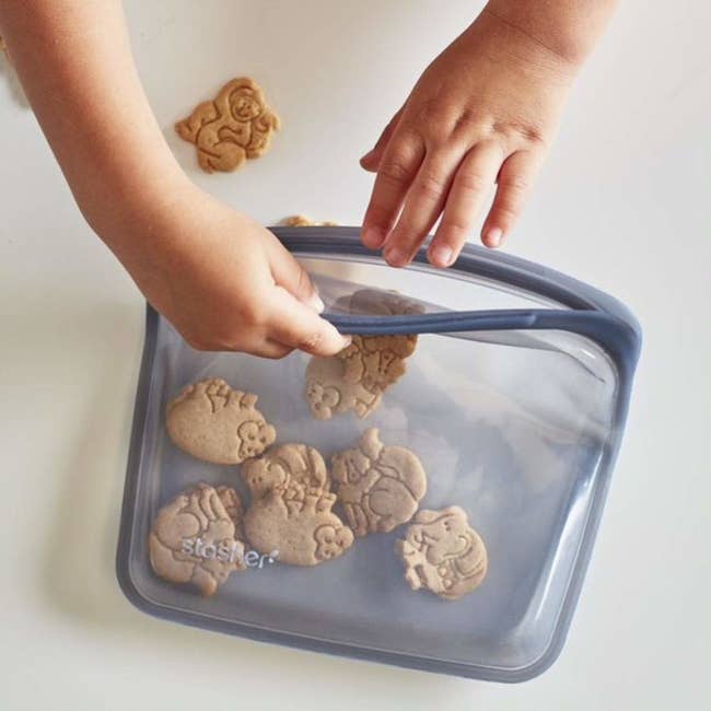 child's hand reaching for animal crackers in the gray bag