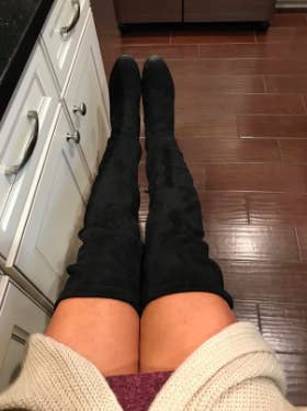 reviewer pic of person wearing a long sweater, short skirt with black ver the knee boots