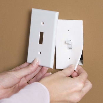 A person installing the light switch socket sealer