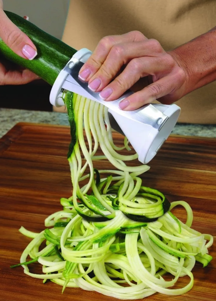 a model&#x27;s hand making zucchini noodles with the slicer