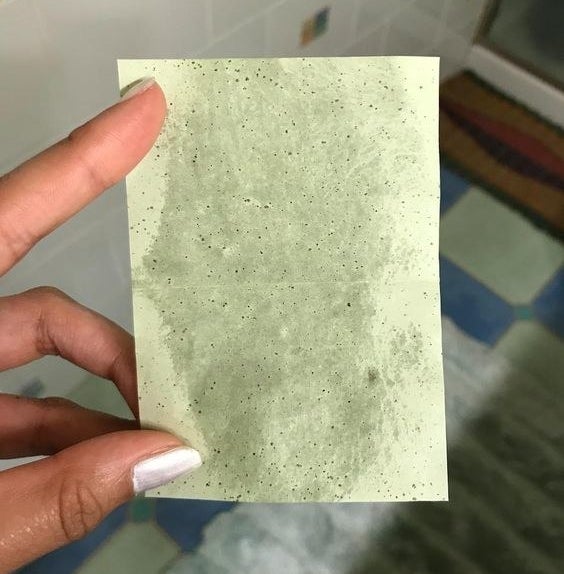 A reviewer holding up a blotting sheet with grease marks on it