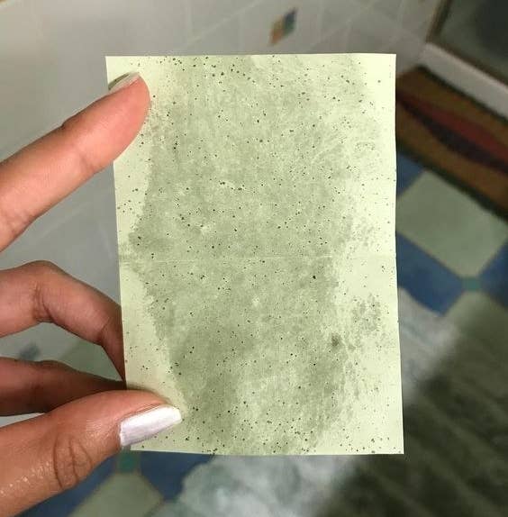 Reviewer holding up a blotting sheet with grease marks on it
