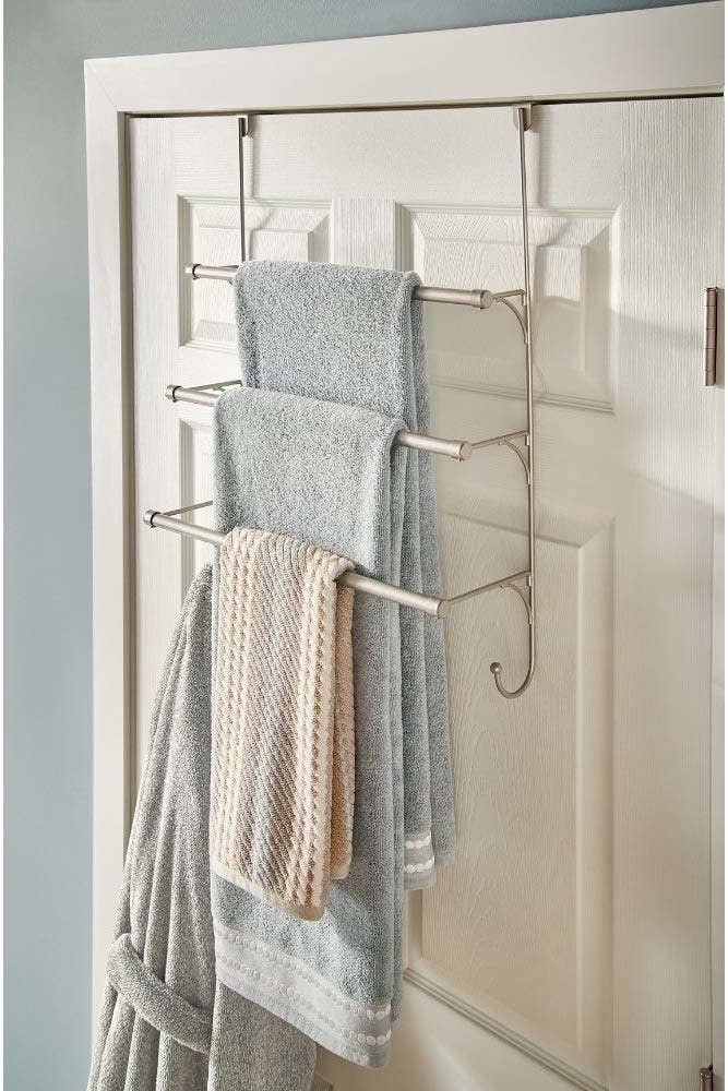 back of bathroom door with a towel rack that has three tiers of racks for towels