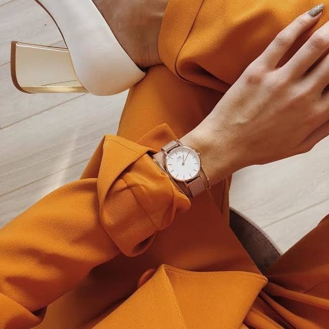 model wearing gold watch with white face