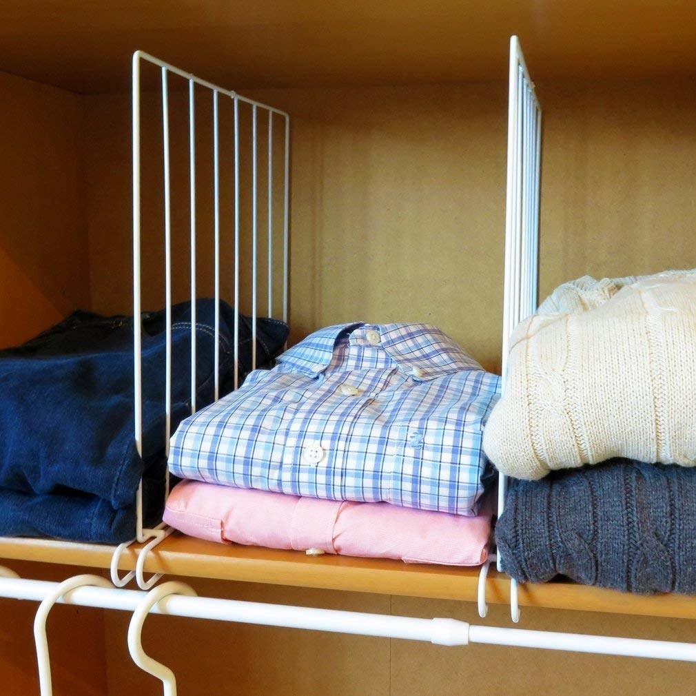 shelf in a closet with dividers between stacks of sweaters and shirts