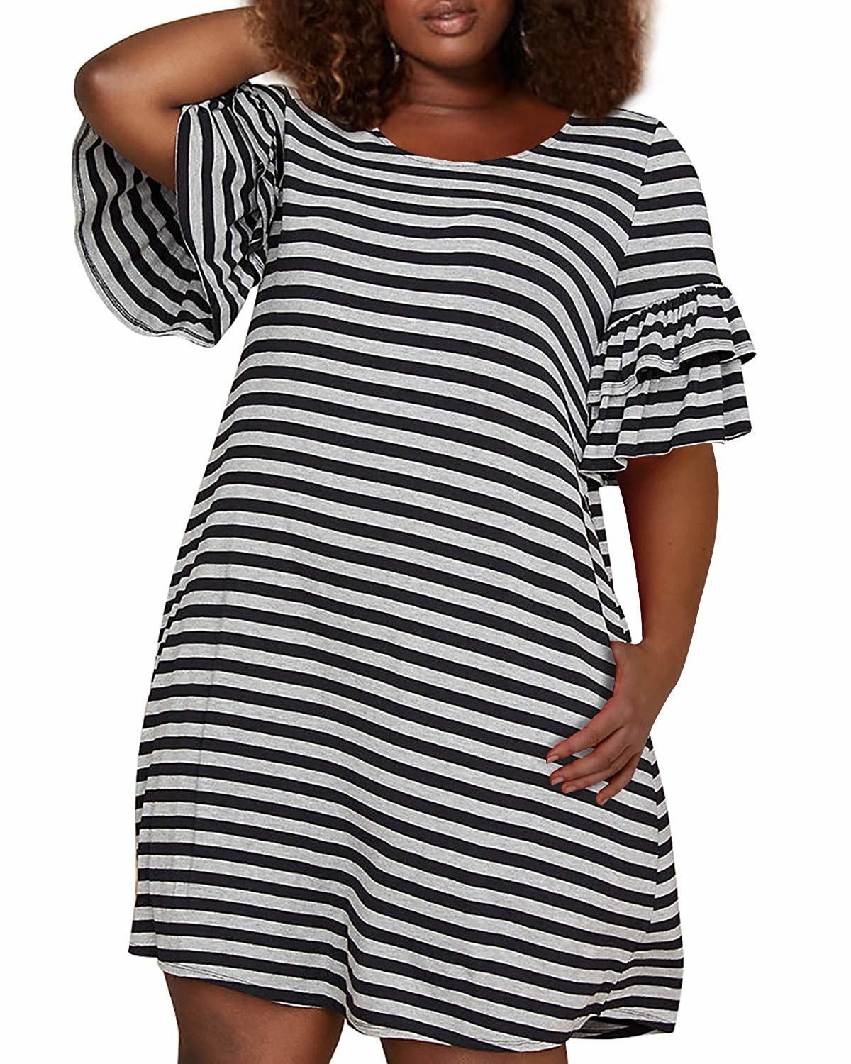 A plus-size model with one hand above their head and the other hand inside one of the pockets. The dress hits right at their thigh with ruffled sleeves that fall to just above the elbow. 