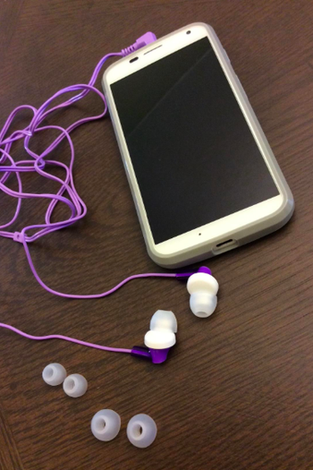 A reviewer's phone attached to the purple headphones, plus the extra, different-sized bud pads
