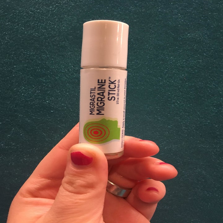 My hand holding up the lipstick-sized tube of the product