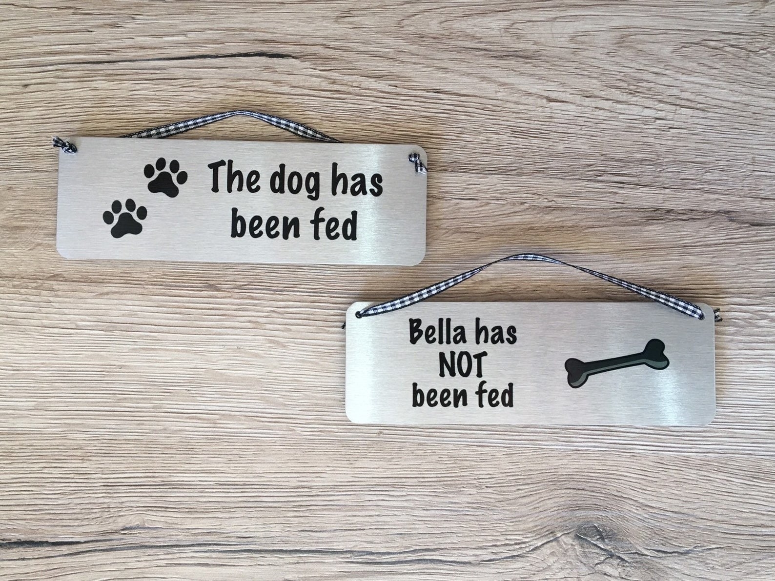 一只狗标签与一个小绳挂在顶部。一边说“狗喂!”另一个标签显示了另一边说,“贝拉没有美联储!”