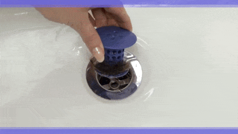 A GIF of a person pulling the silicone, mushroom-shaped product out of their drain. Hair is collected on the 