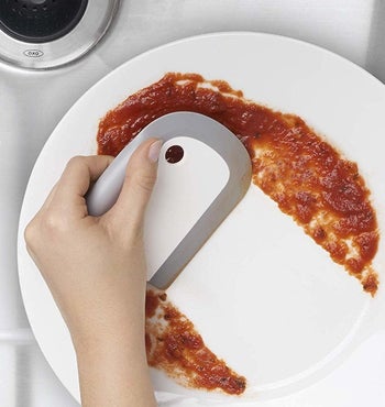 A hand using the squeegee on a plate