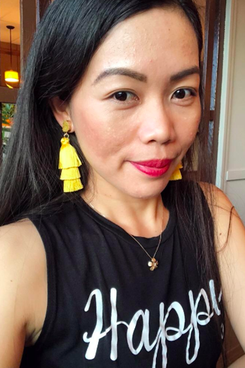 A reviewer wearing the earrings in yellow