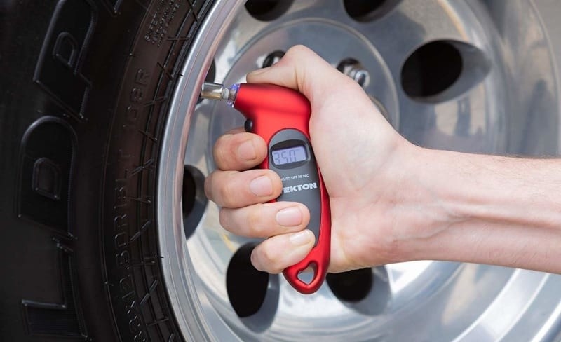 A person taking a tire pressure reading with the gauge