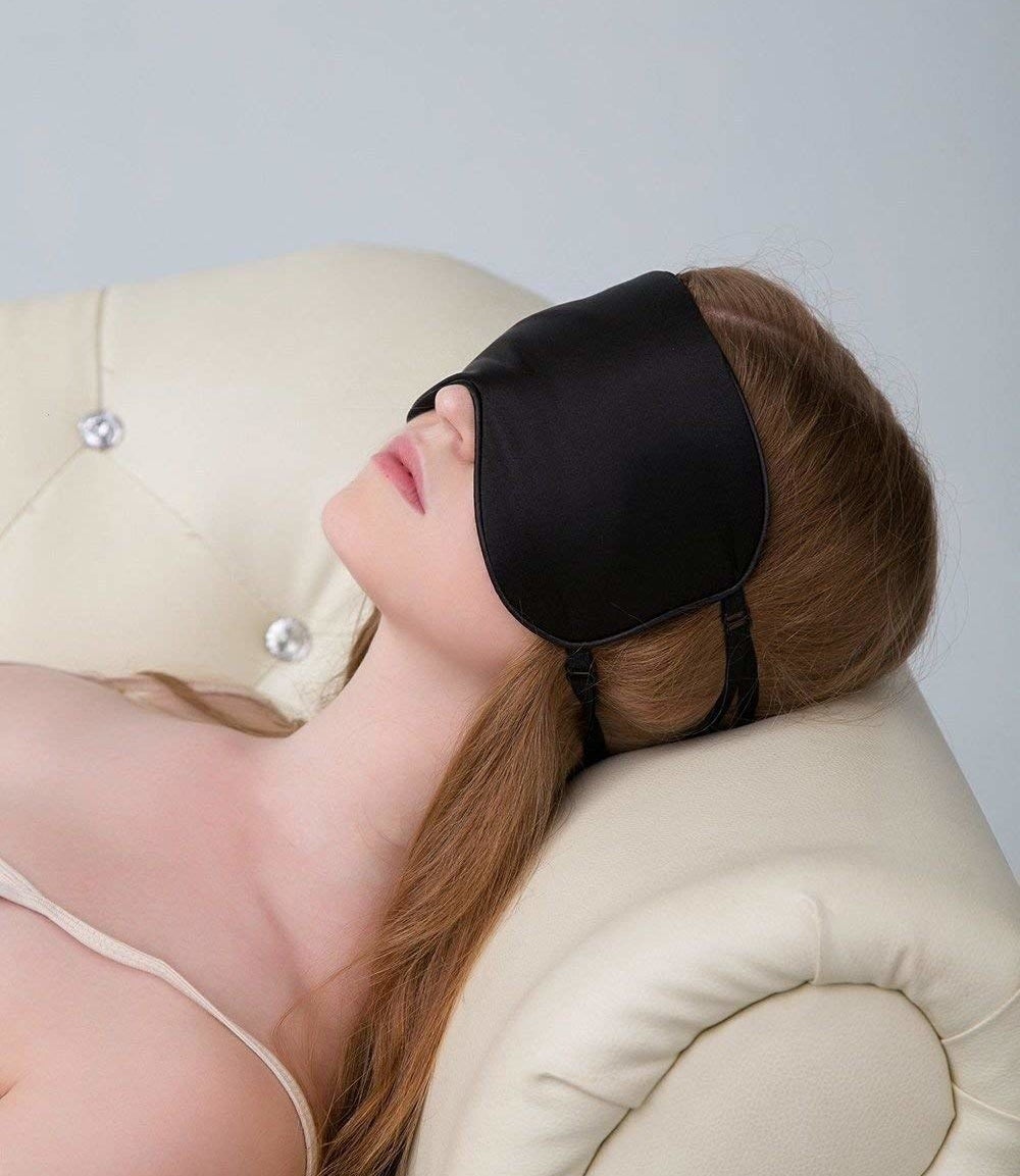 a woman laying on the couch with an eye mask over her face
