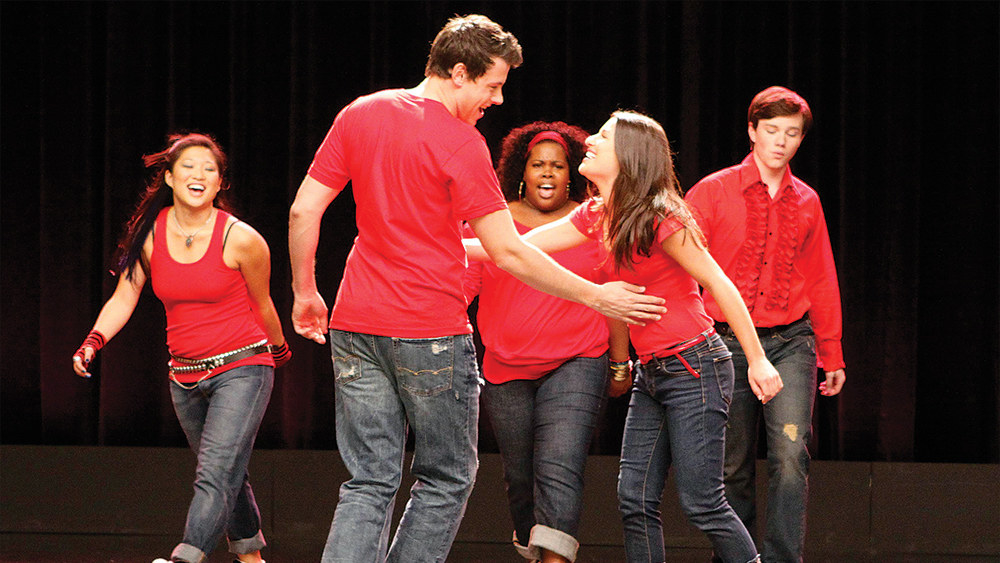 the characters in jeans and matching color shirts performing on stage