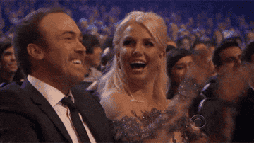 Britney smiling and thumping the palms of her raised hands together