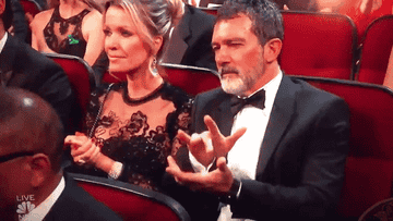 Antonio barely touching one finger to the other hand at an event and not smiling