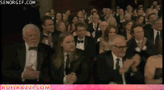 Animated GIF of Nick at a crowded award ceremony hitting one still hand with the other