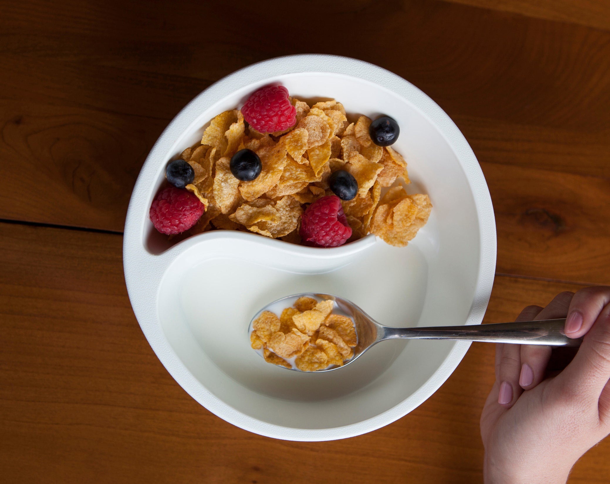 the cereal bowl in white with two section, one filled with dry cereal and the other filled with milk 