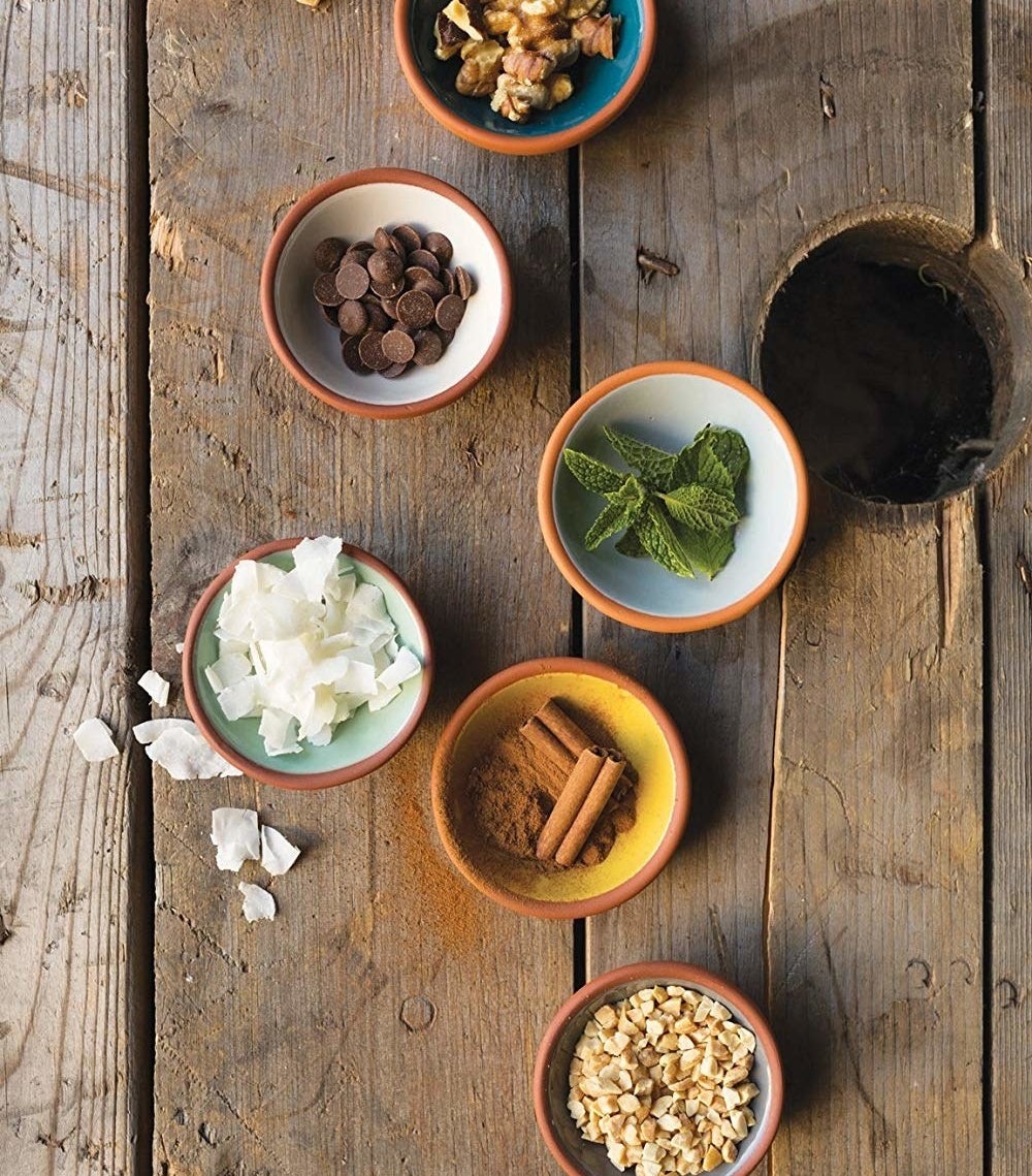 A set of terracotta pinch bowls with various spices and ingredients inside of them