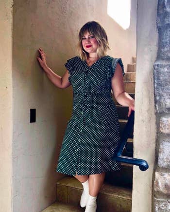 A reviewer wearing the ruffled short sleeve dress with a tie waist that hits just below the knee in green with white polka dots