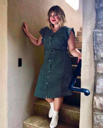 A reviewer wearing the ruffled short sleeve dress with a tie waist that hits just below the knee in green with white polka dots