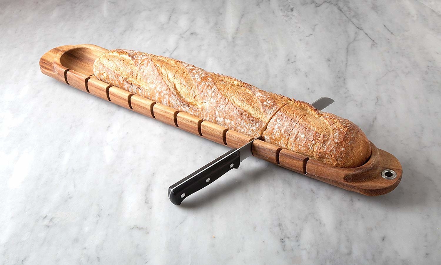 A knife slicing through a baguette on the miter