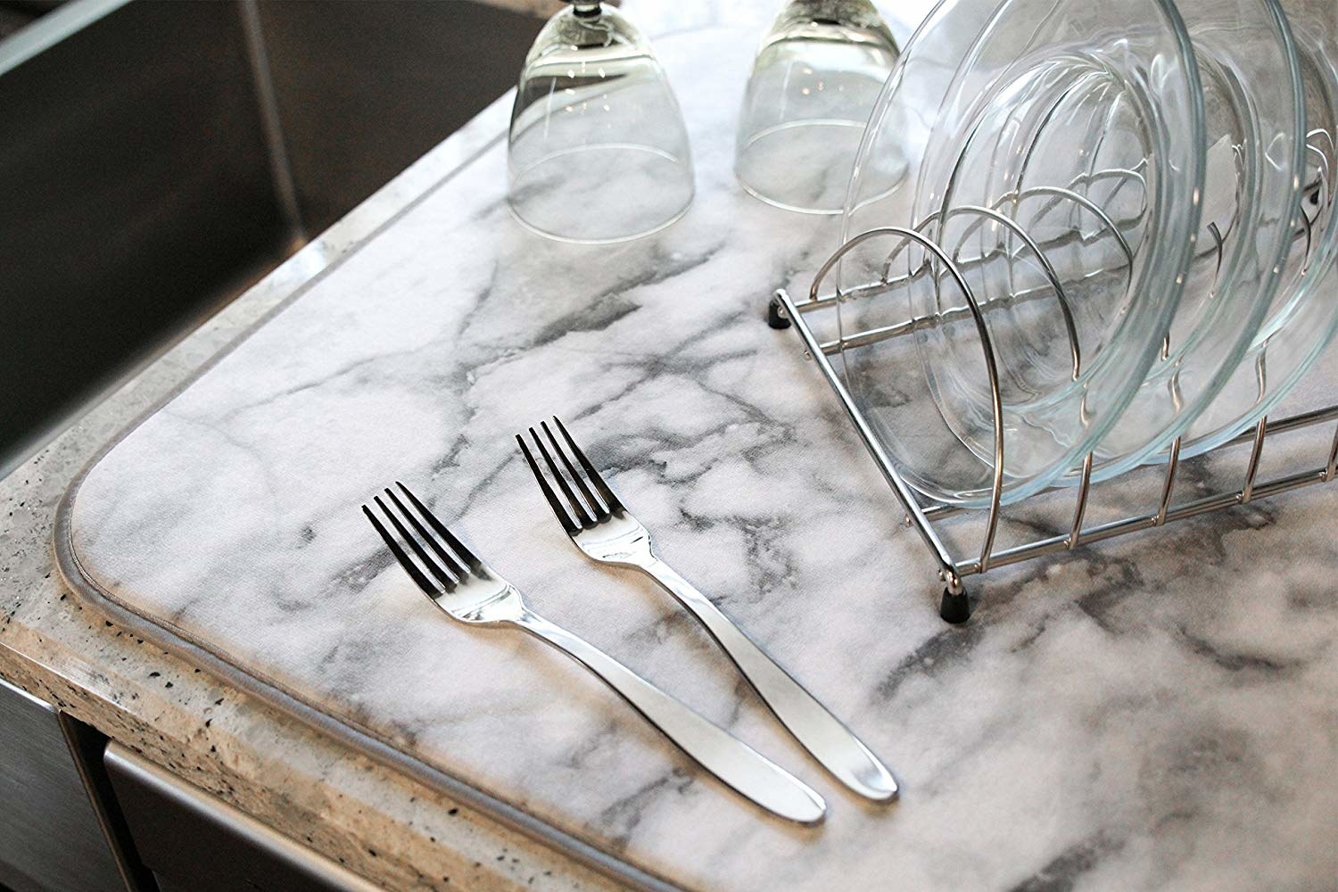 A marble drying mat with clean dishes on top of it