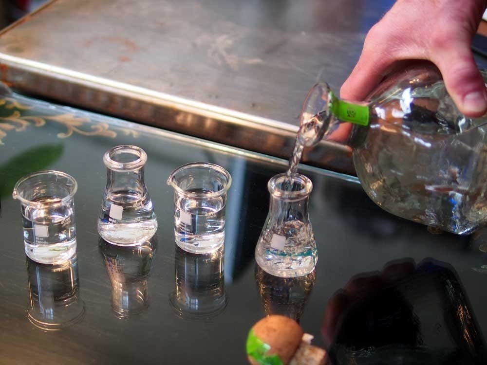 model hand pouring tequila into beaker shot glasses