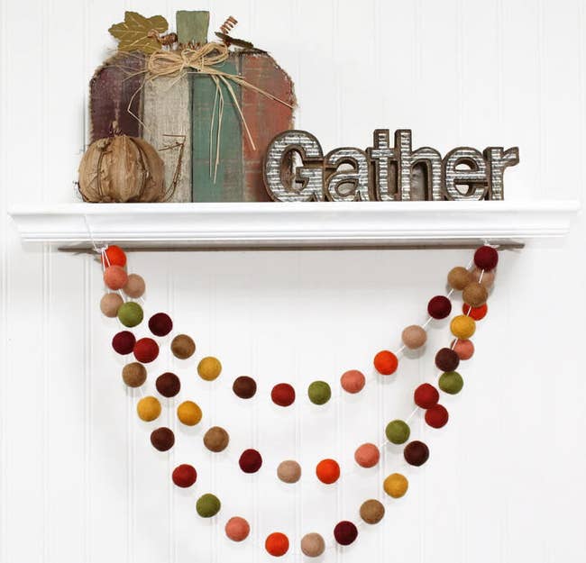 The garland has felt balls in shades of green, red, brown, and yellow