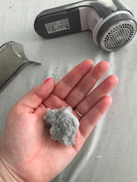 a customer holding a handful of fabric after using the fabric shaver