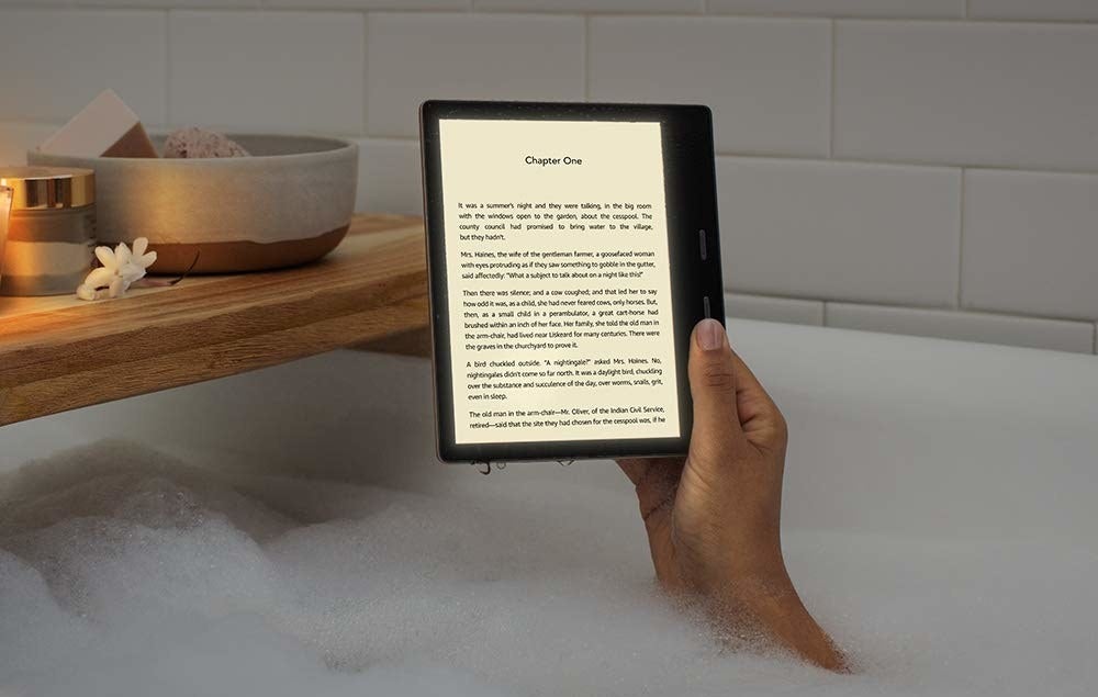 a hand holding up a kindle in the bathtub