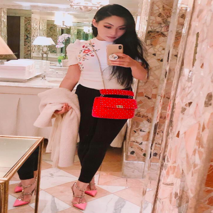 A reviewer wearing the top in white with floral embroidery