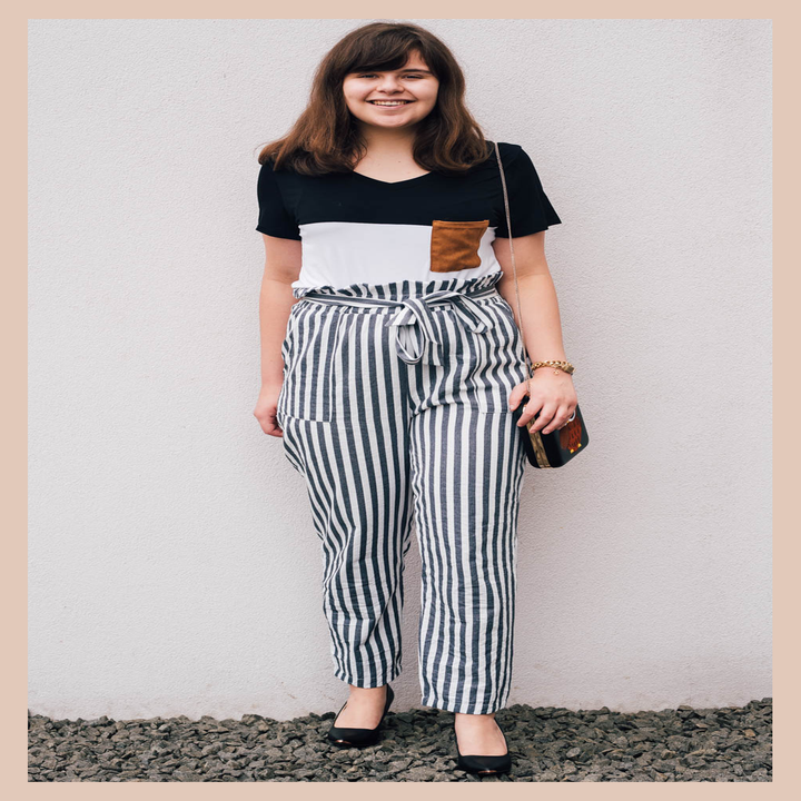 Me wearing the black and white short-sleeve tee with brown pocket tucked into striped pants