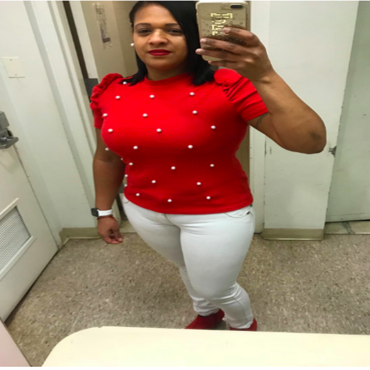 A reviewer wearing the puffed short sleeve top in red with pearl embellishment