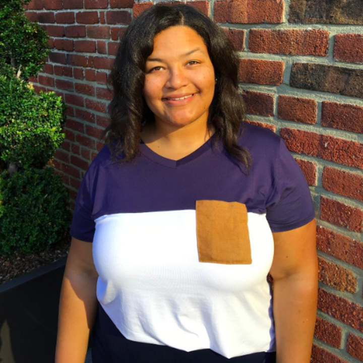 A reviewer wearing the tee in navy and white with brown pocket