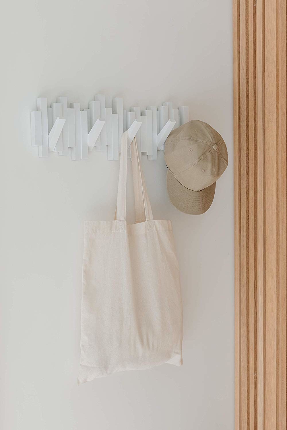 The white hanger, made with abstract blocks, holding a baseball cap and a canvas tote bag