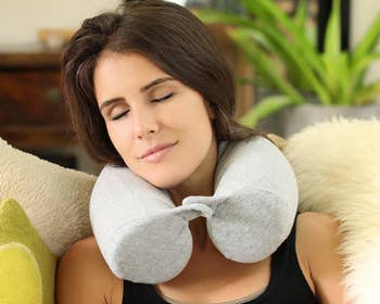 a model with the light grey pillow around their neck