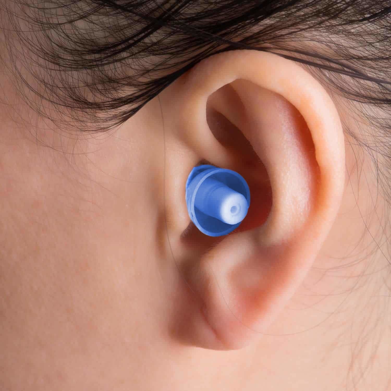 A person with their hair tucked behind their ear wearing an earplug