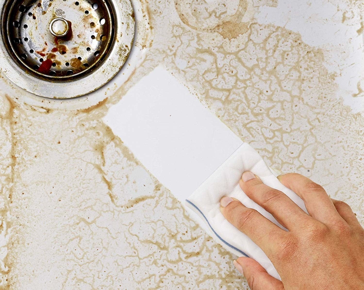 A person using the sponge to clean the dirt in a sink