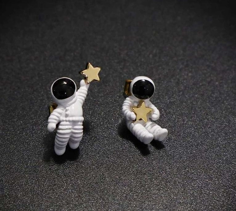 mismatched astronaut earrings holding stars 