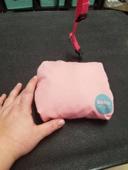 A reviewer's duffel in pink folded up small, about the size of their hand