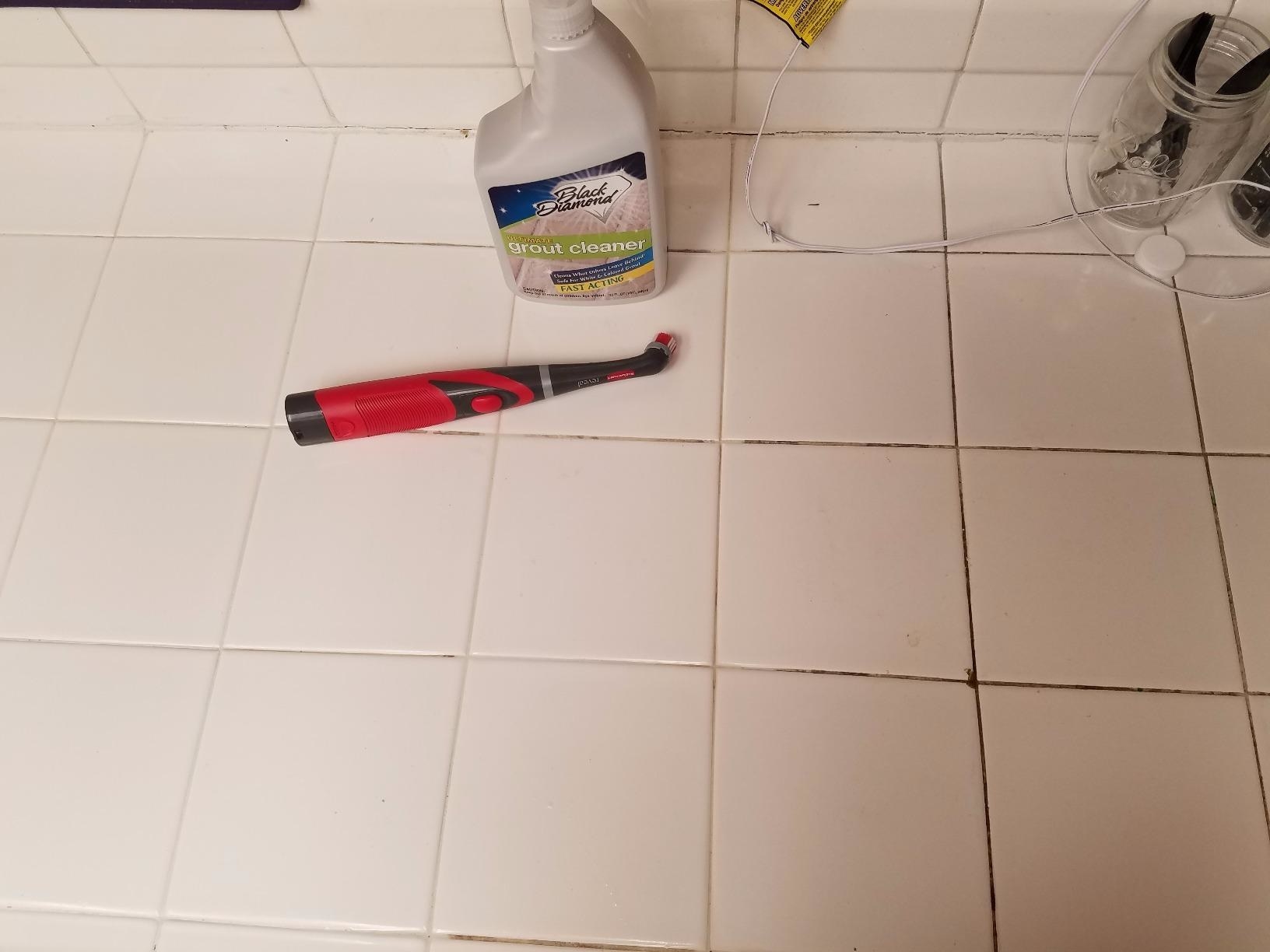 Reviewer photo of their tile grout, which is is white and clean where the scrubber has been used and dark brown where it still needs to be brushed