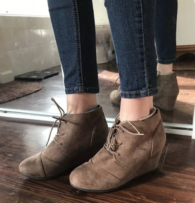 reviewer wearing the brown suede wedge boots